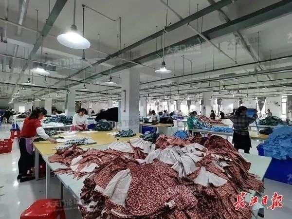 湖北億鑫服饰有限公司的工人们在天门的生产车间里代工女装。